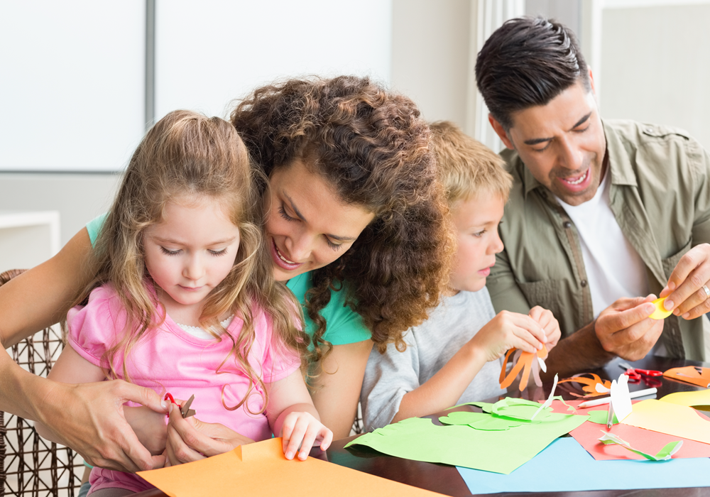 Family of four doing arts and crafts at a table in an apartment home.