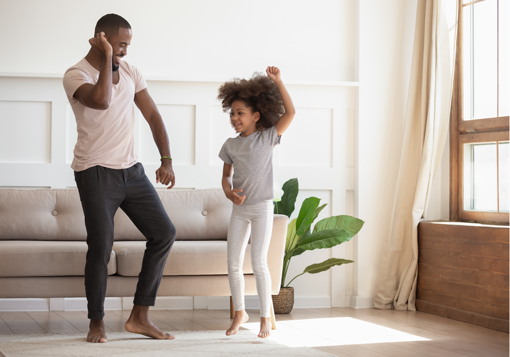 Father and daughter dancing in their apartment home.