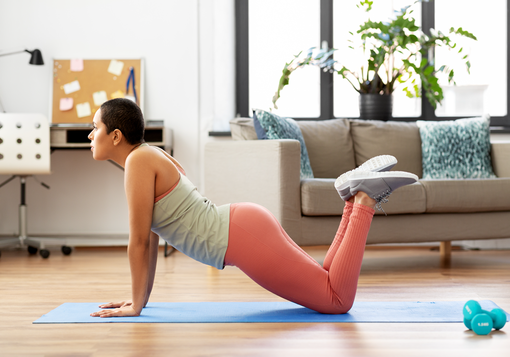 Woman practicing a yoga stretch in her apartment home.