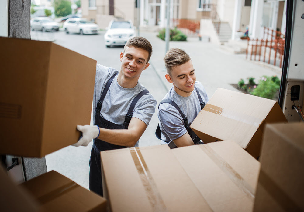 Two hired movers loading boxes on truck for new residents