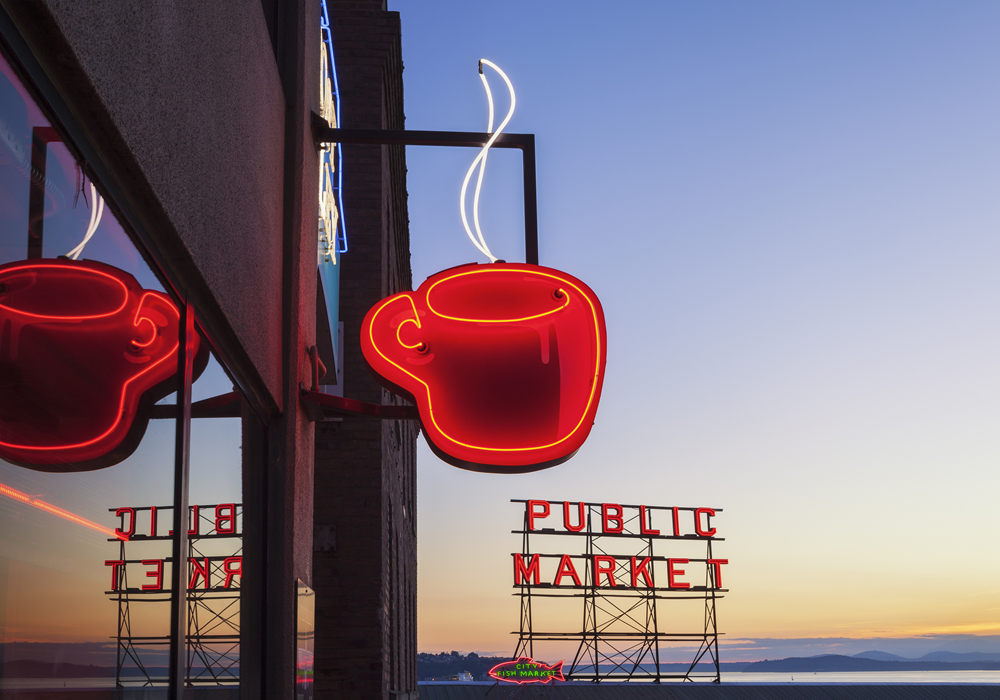 Red coffee shop sign near the Public Market in Seattle at dusk.