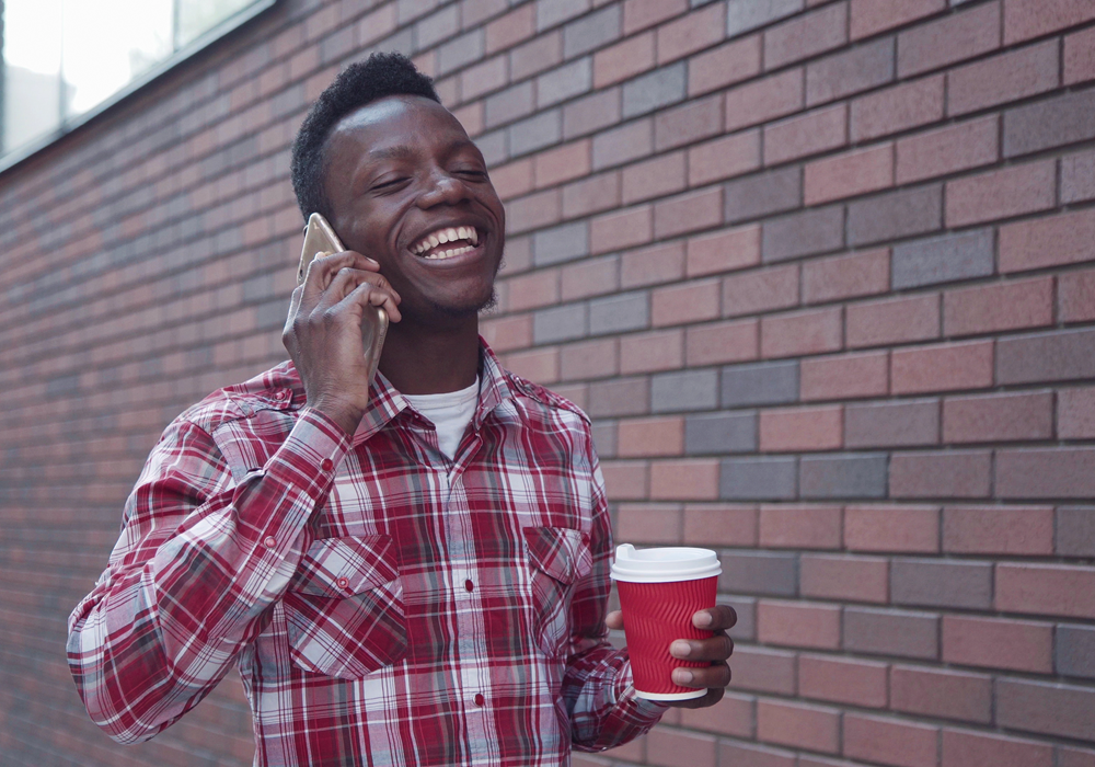 Man on the phone with a cup of coffee in hand.