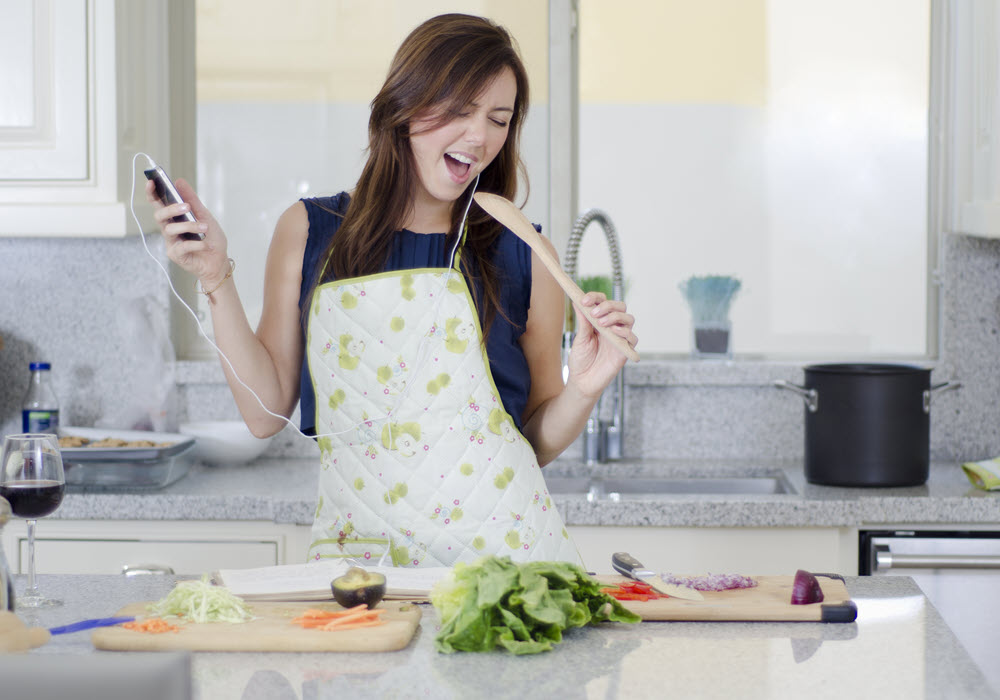 Woman listening to music as she meal preps in an apartment kitchen.