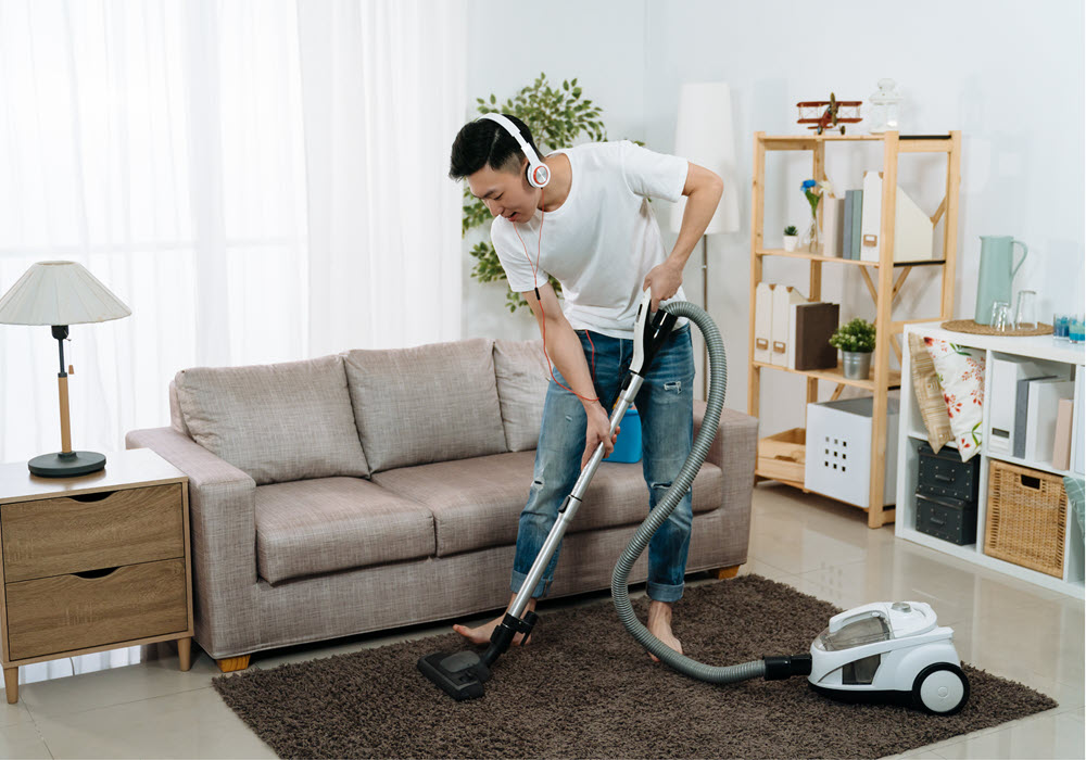 Man listening to music while cleaning his apartment home.