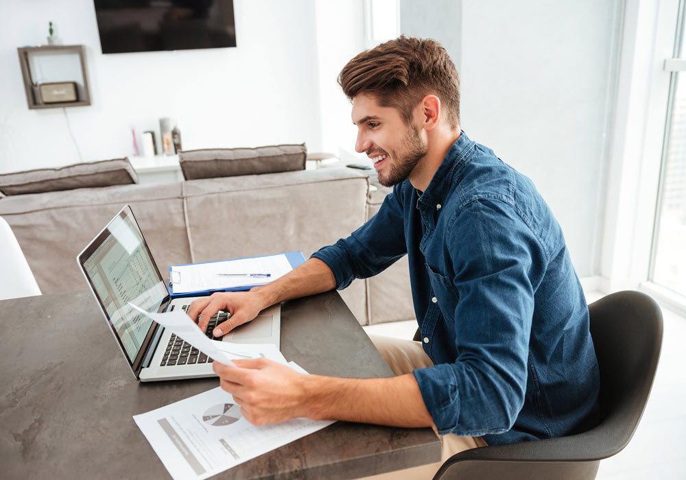 Man checking his credit score via his laptop from his apartment home.