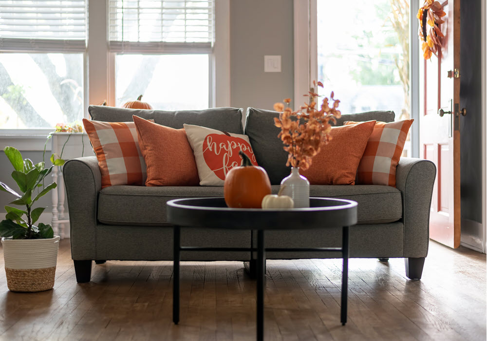 Staged couch with fall decor in living room.