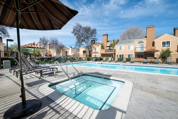 Outdoor swimming pool and spa surrounded by lounge chairs.