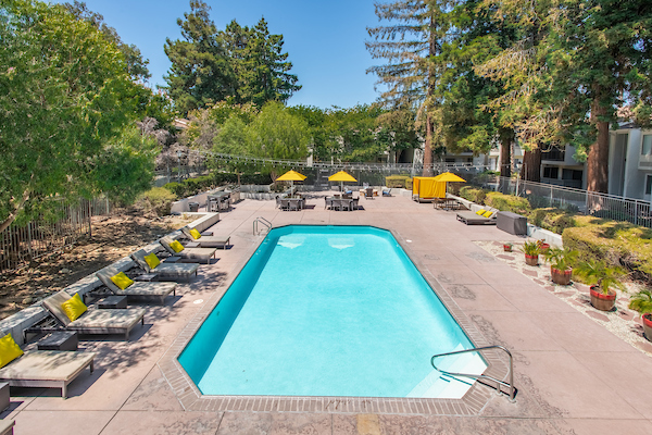 Outdoor swimming pool area with sundeck, lounge seating, and umbrellas.