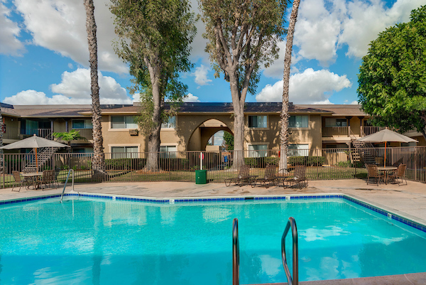 Outdoor swimming pool area surrounded by patio tables with umbrellas.